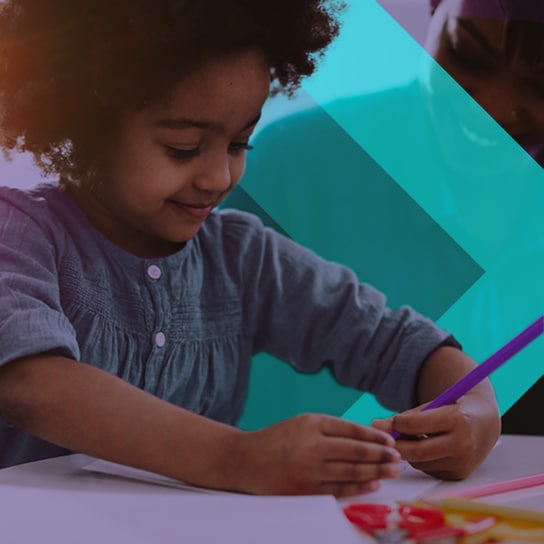 A young child colours in an educational colouring book.