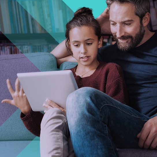 A father and daughter read an education story on the family tablet.